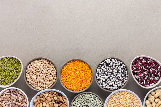 Different types of legumes in bowls, green and yellow peas, chickpeas and peanuts, colored beans and lentils, mung beans and beans, top view - Photo, Image
