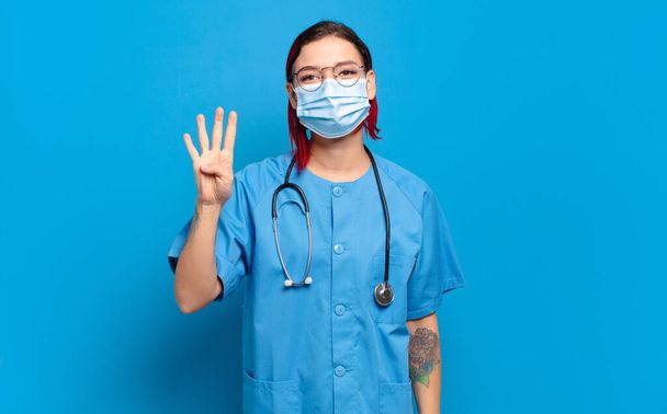 young attractive red hair woman smiling and looking friendly, showing number four or fourth with hand forward, counting down. hospital nurse concept - Φωτογραφία, εικόνα