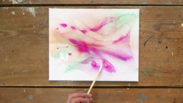 Nestetaidetta. Mies taiteilija käyttää sivellin ja veden tehdä abstrakti värikäs maalaus - Materiaali, video