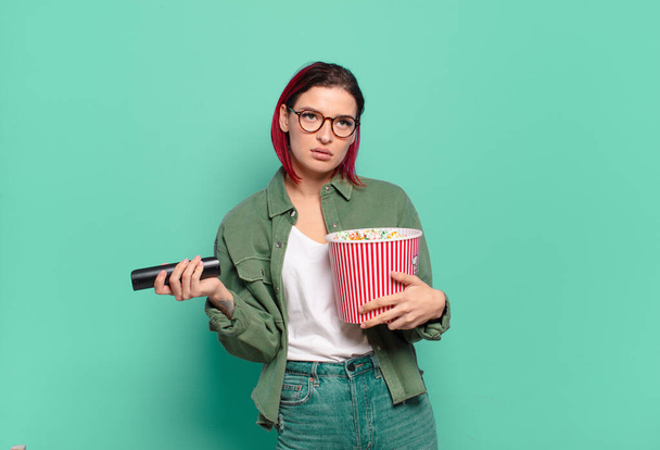 red hair cool woman with popcorns and a tv remote control - Photo, Image