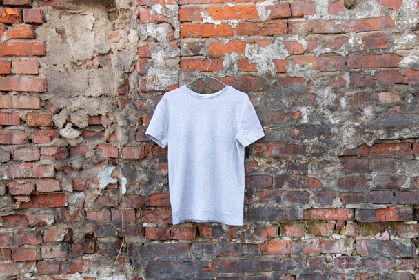 lehký svetr visí na ramínku na cihlové zdi na ulici, módní dámské oblečení - Fotografie, Obrázek