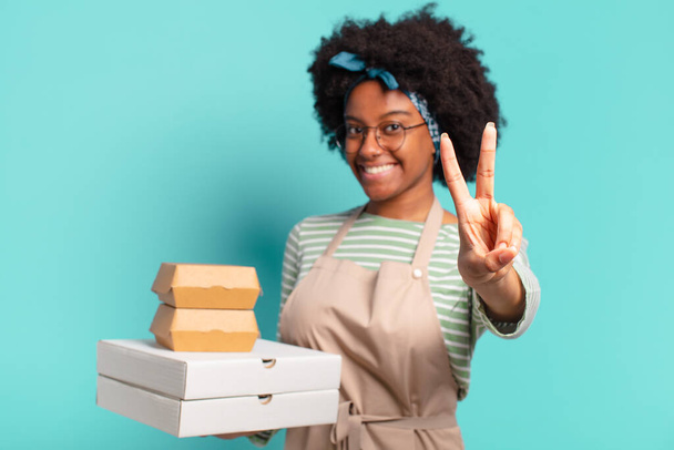 молода красива афро-доставка жінка з забиранням піци і бургерів коробки
 - Фото, зображення