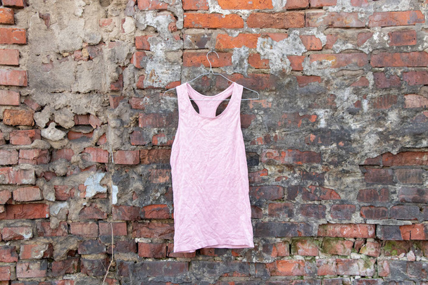 ροζ εσώρουχα γυναικών δεξαμενή κορυφή κρέμεται σε μια κρεμάστρα σε έναν τοίχο από τούβλα στο δρόμο, μόδα γυναικεία ρούχα - Φωτογραφία, εικόνα