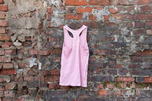 Pembe iç çamaşırlı kadın gömleği askıda asılı tuğla bir duvarda, moda kadın kıyafetleri - Fotoğraf, Görsel