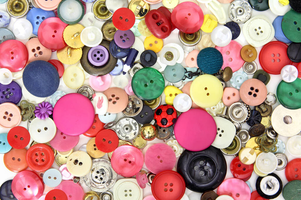 Set di bottoni e accessori per il cucito in colori, dimensioni e forme molto diverse. Principalmente rosa e rosso e alcuni pulsanti gialli, blu e verdi - Foto, immagini