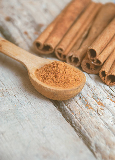 Cinnamon powder in a wooden spoon next to cinnamon sticks. - Photo, Image