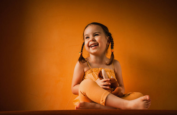 Dziewczynka śmieje się na pomarańczowym tle - Zdjęcie, obraz
