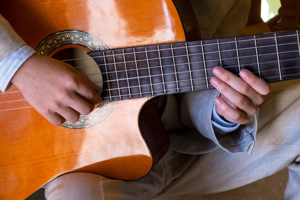 dettaglio delle mani di un ragazzo bianco che suona la chitarra spagnola. - Foto, immagini