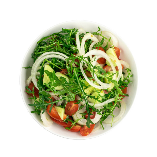 Arugula saláta fehér tálcán izolálva. Friss arugula saláta rukkolalevéllel, paradicsommal, uborkával és hagymával felülnézetből - Fotó, kép