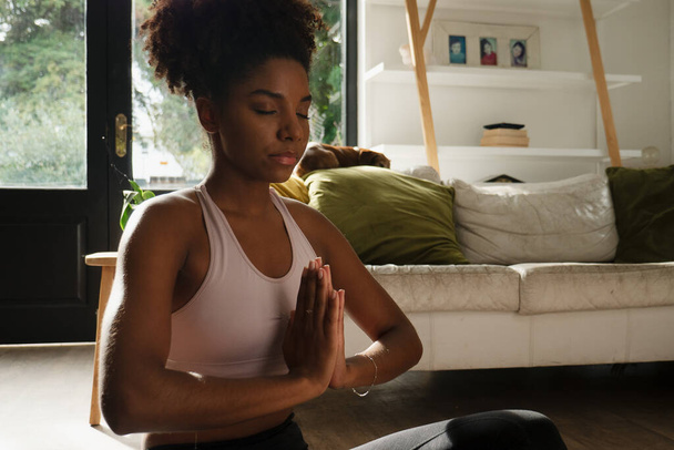 Vrouwelijke tiener met bidpositie tijdens de yogaflow zittend in de moderne lounge - Foto, afbeelding