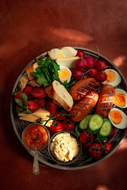 Reggeli vagy villásreggeli tálca különféle ételekkel az egész család számára terrakotta alapon, felülnézetből - Fotó, kép