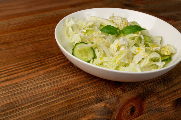 Salade de chou chinois avec Napa ou Wombok sur fond de table en bois. Salat de chou vert frais tranché aux concombres, oignons et herbes - Photo, image