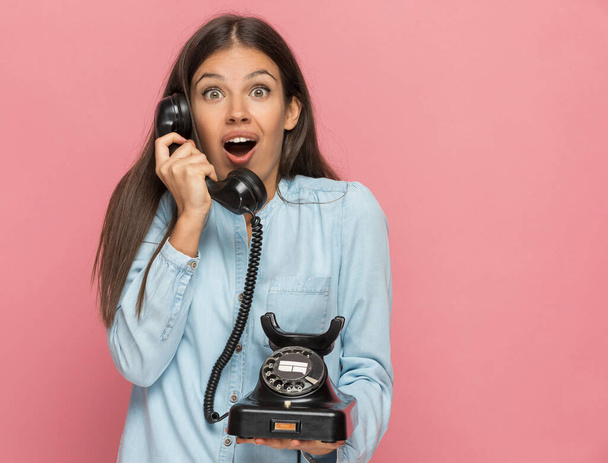 krásná ležérní žena pocit šoku po telefonátu na růžovém pozadí - Fotografie, Obrázek