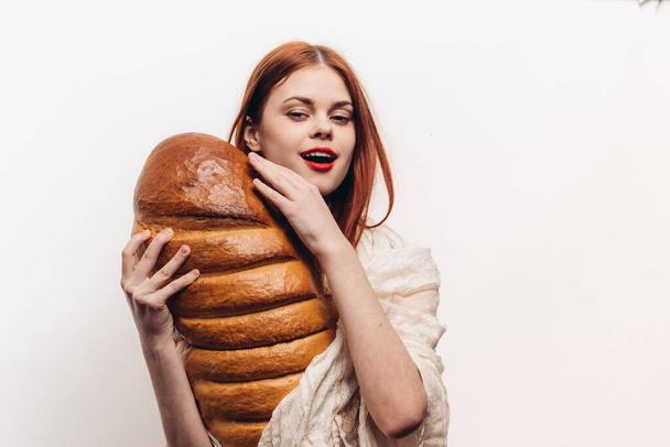 mujer abraza pan fresco con sus manos sobre un pan de fondo claro de productos de harina de pan - Foto, Imagen
