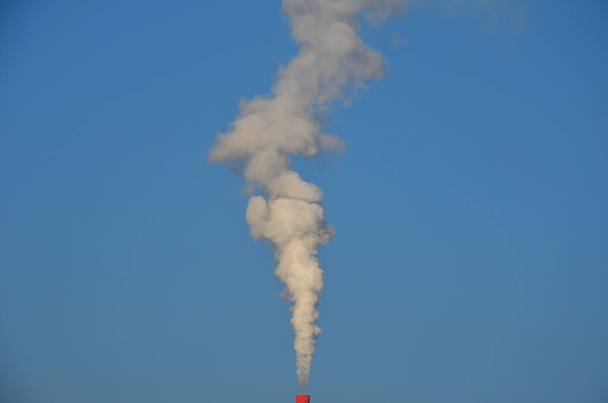 Harmless white smoke from a large city's waste incinerator is already clean. The incinerator produces electricity for households. a chimney from which a tall column of smoke emerges stock photo - Photo, Image