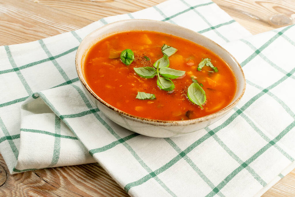 Красный томатный суп с ячменем и овощами. Домашний кремовый харчо, харчо суп с картошкой, морковью, капустой, луком и злаками в белой миске - Фото, изображение