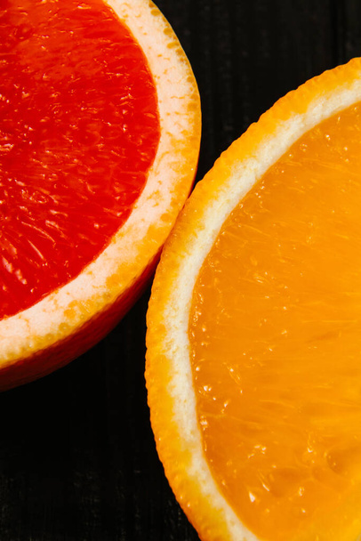 Media naranja fresca y pomelo sobre fondo negro de cerca. Foto de alta calidad - Foto, Imagen
