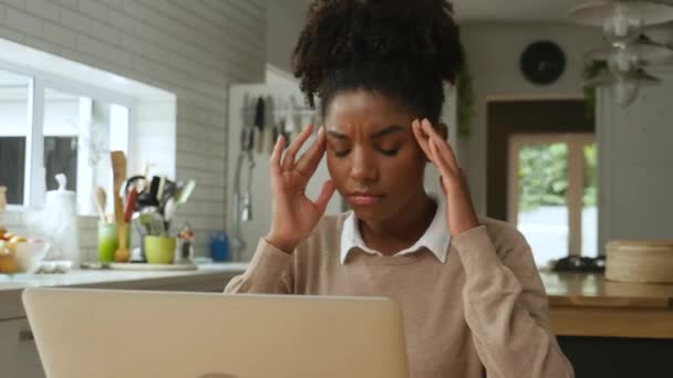 Jonge vrouw met hoofdpijn die thuis werkt, zich gestrest en moe voelt - Video