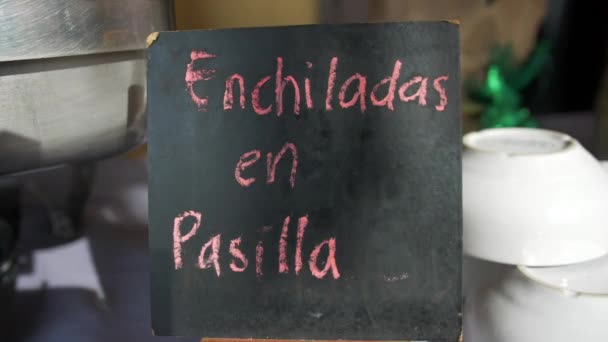 Metalen pot en zwart bordje met roze Spaanse tekst op tafel - Video