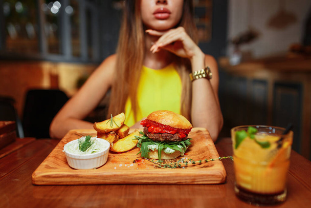 sexy Frau isst leckeren gegrillten saftigen Burger im Restaurant  - Foto, Bild