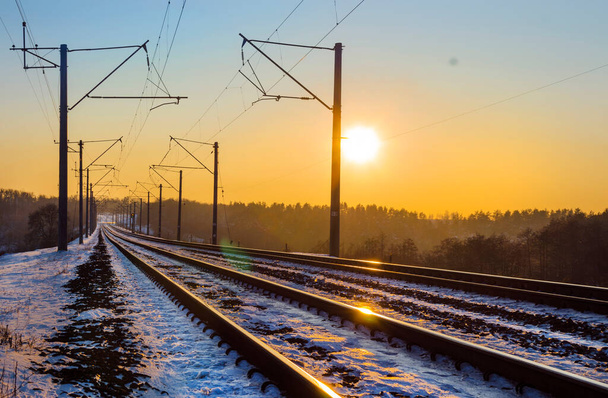 Askelia lumessa pitkin rautateitä talvella auringonlaskun aikaan - Valokuva, kuva