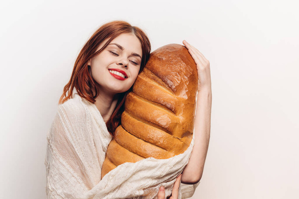 mulher com maquiagem brilhante abraçando um grande pão em suas mãos - Foto, Imagem