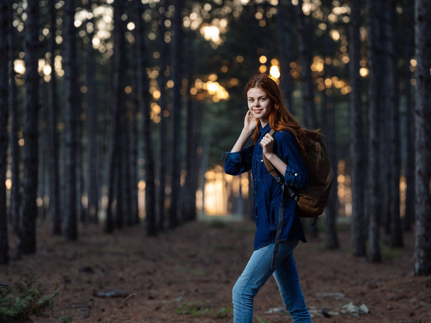 Kobieta podróżuje wśród drzew w lesie jesienią i zachodem słońca w tle - Zdjęcie, obraz