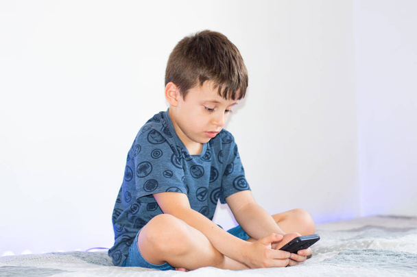 Niño usando un teléfono inteligente con un fondo blanco - Foto, Imagen