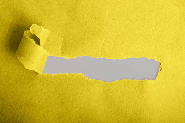 Κίτρινο torned χαρτί με γκρι υπόστρωμα από κάτω του.Μοντέρνο χρώμα 2021.Copy space για κείμενο. - Φωτογραφία, εικόνα