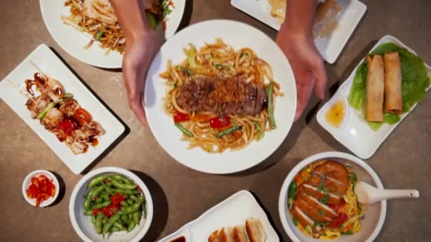 Comida tradicional asiática con carne asada y brotes de frijol sobre la mesa. Vista aérea de servir platos asiáticos y aperitivos en múltiples platos - Metraje, vídeo