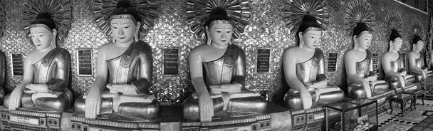 Monochrom anmutende Reihe goldener Buddhas im Mandalay-Tempel in Myanmar. Hochwertiges Foto - Foto, Bild