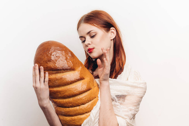 vrouw knuffelt vers brood met haar handen op een lichte achtergrond brood bloem producten - Foto, afbeelding