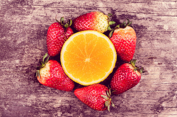 Strawberries and oranges on wood - Фото, изображение