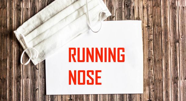 Słowo RUNNING NOSE jest napisane na notatniku, obok maski medycznej - Zdjęcie, obraz