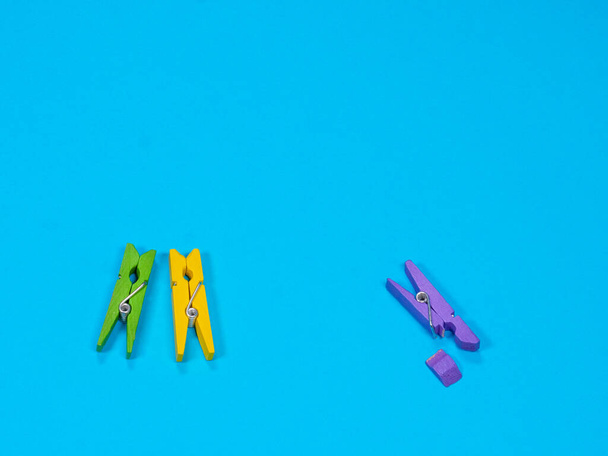 Violet wooden clothespin with fracture leg on blue background - Photo, Image