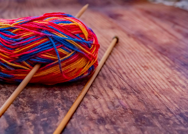 コピースペースのある堅木張りの床に竹編み針で毛糸の多色のボールを閉じて選択的な焦点 - 写真・画像