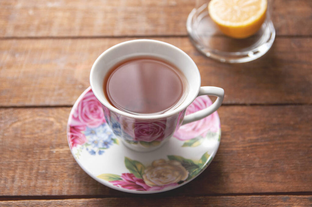 mesa, taza de té con limoncillo de vidrio sobre un fondo de madera - Foto, imagen