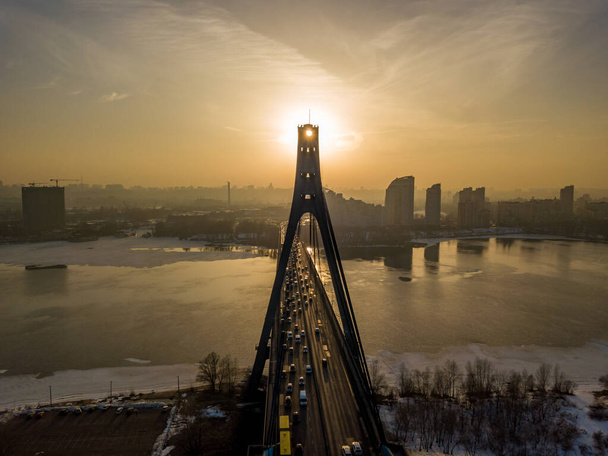 Północny most w Kijowie o zachodzie słońca. Widok z lotu ptaka. Wiosenny wieczór, promienie słoneczne przechodzą przez filary mostu. - Zdjęcie, obraz