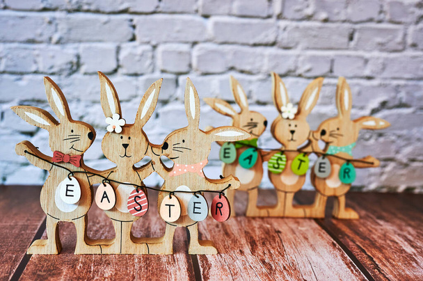 Ξύλινα πασχαλινά λαγουδάκια με διακόσμηση και το κείμενο Πάσχα γραμμένο στα αυγά. - Φωτογραφία, εικόνα