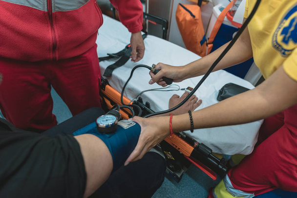 egészségügyi dolgozók egy csoportja segít a betegnek a mentőben elvégezni a vizsgálatokat. - Fotó, kép