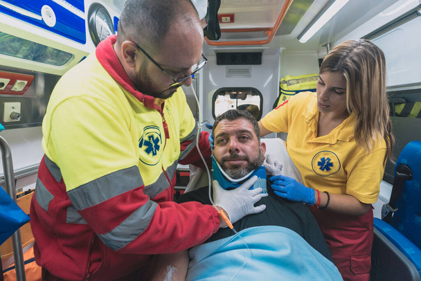 una squadra medica in ambulanza aiuta un uomo adulto - Foto, immagini