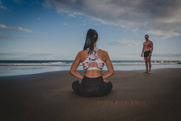 young man and woman exercise on the beach outdoors in a healthy way - Photo, Image