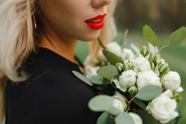 Закройте женщину с красными губами, смотрящую на белые цветы. Фон с местом для вашего текста - Фото, изображение