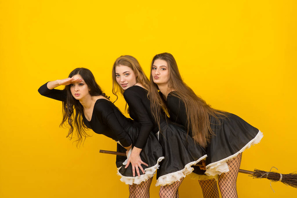 Drei sexy Dienstmädchen auf dem Besen im Studio, Hexen, böse Geister. - Foto, Bild