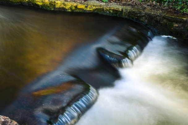 川の流れの速い水と水しぶき晴れた日に森の中に落ちる - 写真・画像