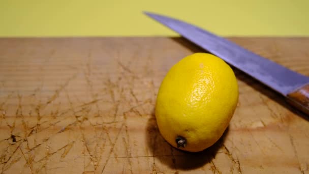 Découpe et tranchage d'un citron sur une plaque de bois à l'aide d'un couteau métallique et de mains d'homme. - Séquence, vidéo