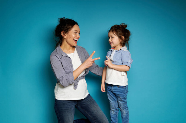 Matka a dcera hrají hru na kámen-nůžky-papír. Pojem mateřství a dětství. Modré pozadí a kopírovat prostor - Fotografie, Obrázek