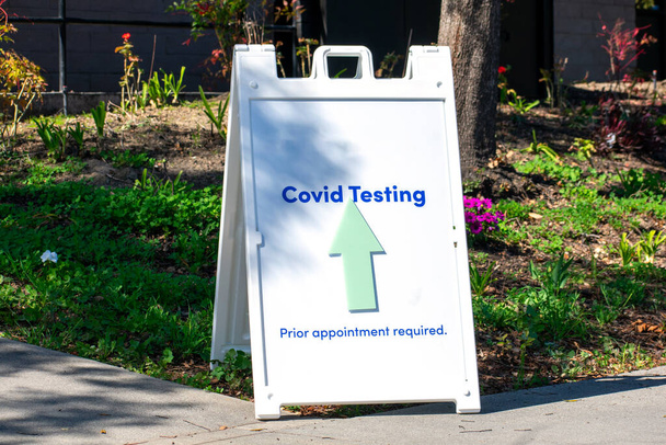 Covid testen, voorafgaande afspraak vereist teken met een pijl leidt bezoekers naar coronavirus testcentrum locatie. - Foto, afbeelding