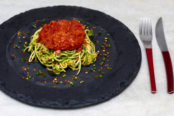 Zucchini-Spaghetti mit dehydriertem Pfeffer und roter Sauce. - Foto, Bild