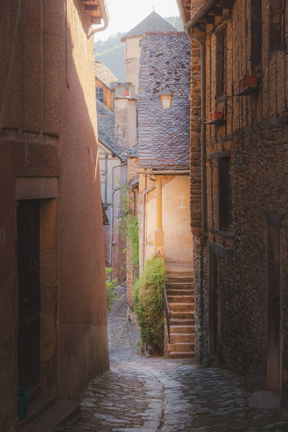 Un carril rural en el pintoresco y encantador pueblo medieval francés de Conques, Aveyron, un popular destino turístico de verano en la región de Occitanie de Francia. - Foto, Imagen